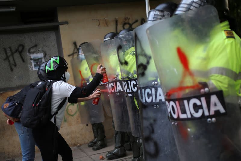 Manifestantes pintan los escudos antidisturbios de los policías durante una protesta frente a una estación policial después de que un hombre, que fue detenido por violar las normas de distanciamiento social, murió tras recibir sucesivas descargas eléctricas con una pistola paralizante en Bogotá