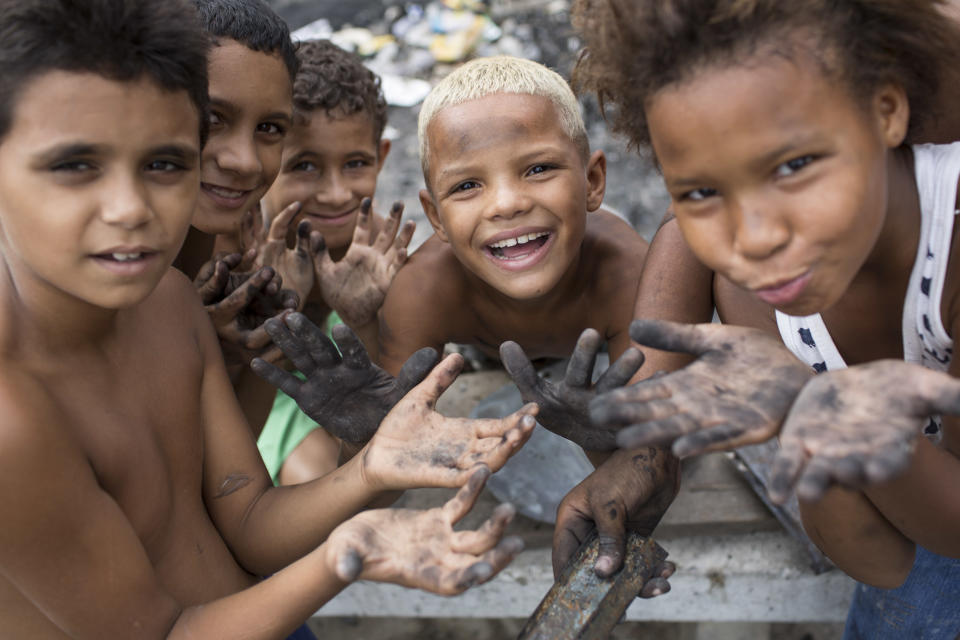 Young residents show their soot-stained hands after searching for valuable items in the burned remains of a Pacifying Police Unit post at the Mandela shantytown, part of the Manguinhos slum complex, in Rio de Janeiro, Brazil, Friday, March 21, 2014. Rio de Janeiro police say suspected drug gang members on Thursday night attacked three police slum outposts and burned one of them. Officials say they'll ask for elite Brazilian federal police to help quell a wave of violence in supposedly pacified slums. (AP Photo/Felipe Dana)