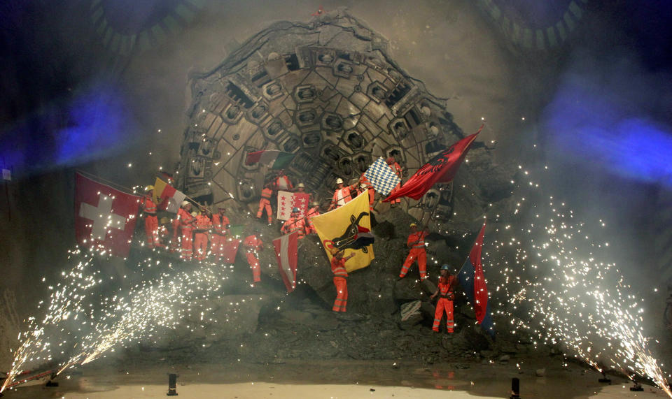 Miners celebrate as fireworks explode after a giant drill machine broke through the rock at the final section Sedrun-Faido, at the construction site of the NEAT Gotthard Base Tunnel