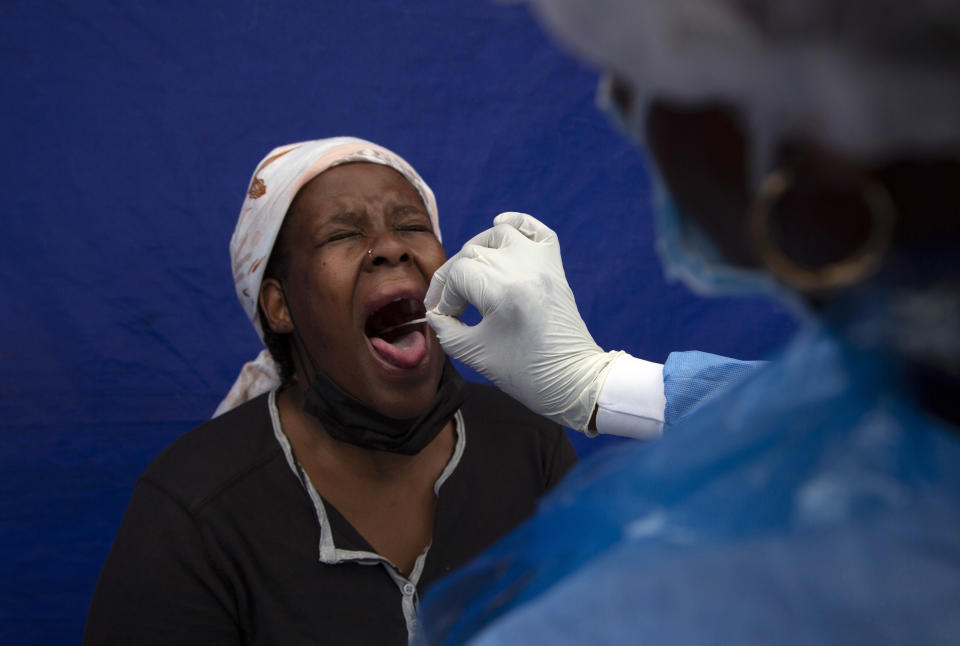 FILE — A throat swab is taken from a patient to test for COVID-19 at a facility in Soweto, South Africa, Dec. 2, 2021. South Africa's noticeable drop in new COVID-19 cases in recent days may signal that the country's dramatic omicron-driven wave has passed its peak, medical experts say. (AP Photo/Denis Farrell, File)