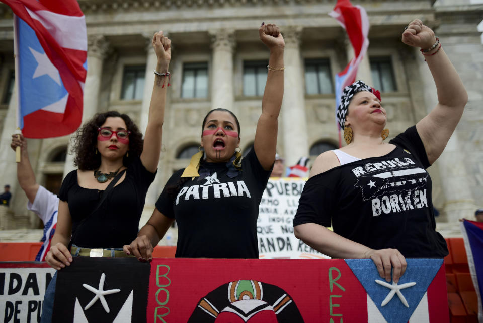Women join a protest organized by Puerto Rican singer Rene Perez of Calle 13 over emergency aid that until recently sat unused in a warehouse amid ongoing earthquakes, in San Juan, Puerto Rico, Thursday, Jan. 23, 2020. Protesters demanded the ouster of Gov. Wanda Vázquez. (AP Photo/Carlos Giusti)