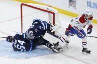 Winnipeg Jets' Logan Stanley (64) crashes into goaltender Connor Hellebuyck (37) as Montreal Canadiens' Brett Kulak (77) skates past during the third period of Game 1 of an NHL hockey Stanley Cup second-round playoff series Wednesday, June 2, 2021, in Winnipeg, Manitoba. (John Woods/The Canadian Press via AP)