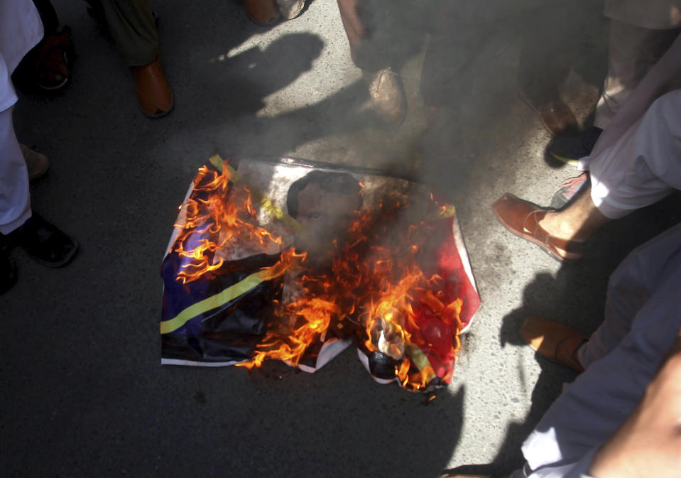 Supporters of the religious student group, Islami Jamiat Tulba, burn a representation of the French flag with an image of French President Emmanuel Macron during a protest against the publishing of caricatures of the Prophet Muhammad they deem blasphemous, in Peshawar, Pakistan, Tuesday, Oct. 27, 2020. (AP Photo/Muhammad Sajjad)