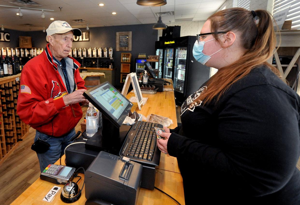 Larry Kyes of Petersburg goes without a mask as he makes a purchase Wednesday from Courtney Gorden at Roberts Seafood Market in Springfield.