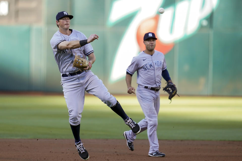 New York Yankees shortstop Isiah Kiner-Falefa, background, watches as second baseman DJ LeMahieu, left, throws to first base for an out against Oakland Athletics' Shea Langeliers during the first inning of a baseball game in Oakland, Calif., Saturday, Aug. 27, 2022. (AP Photo/Godofredo A. Vásquez)