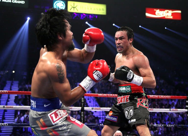 Manny Pacquiao (L) falls to to the canvas after taking a punch from Juan Manuel Marquez in the third round of their welterweight fight on December 8, 2012 in Las Vegas. Marquez knocked out Pacquiao in the 6th round