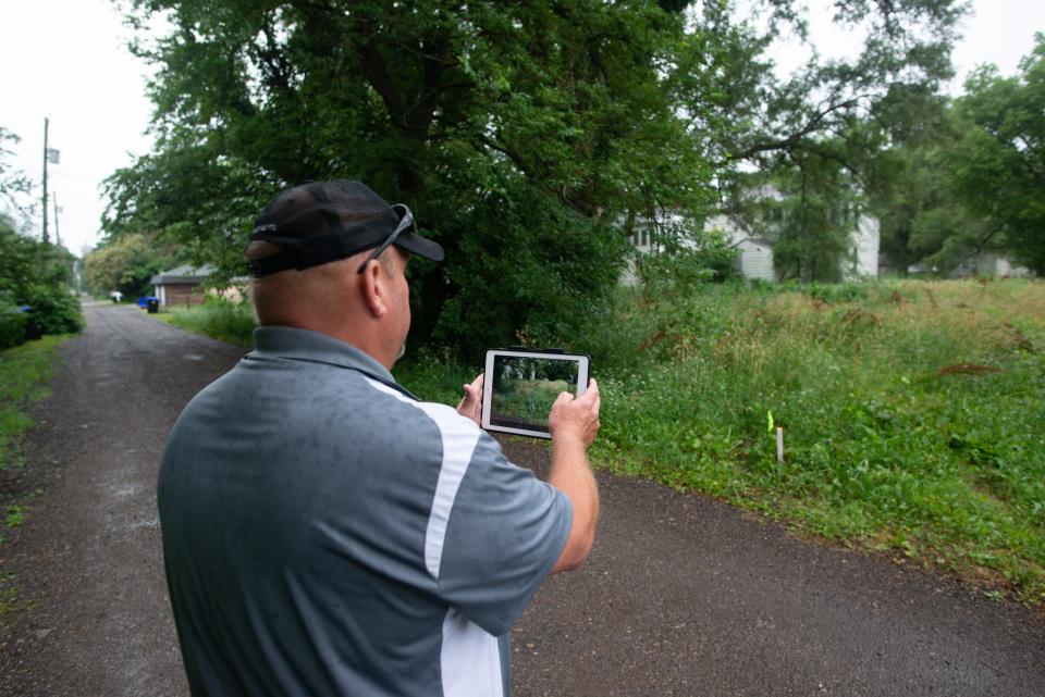 John Schardine, a field supervisor for Topeka's public works department, takes a photo to be saved to an online portal Thursday while recording a violation of the city's property maintenance code.