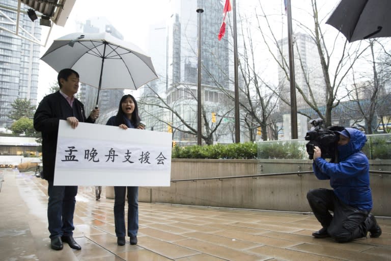 Terence Xu (L) and Ada Yu hold a sign in support of Meng outside her bail hearing