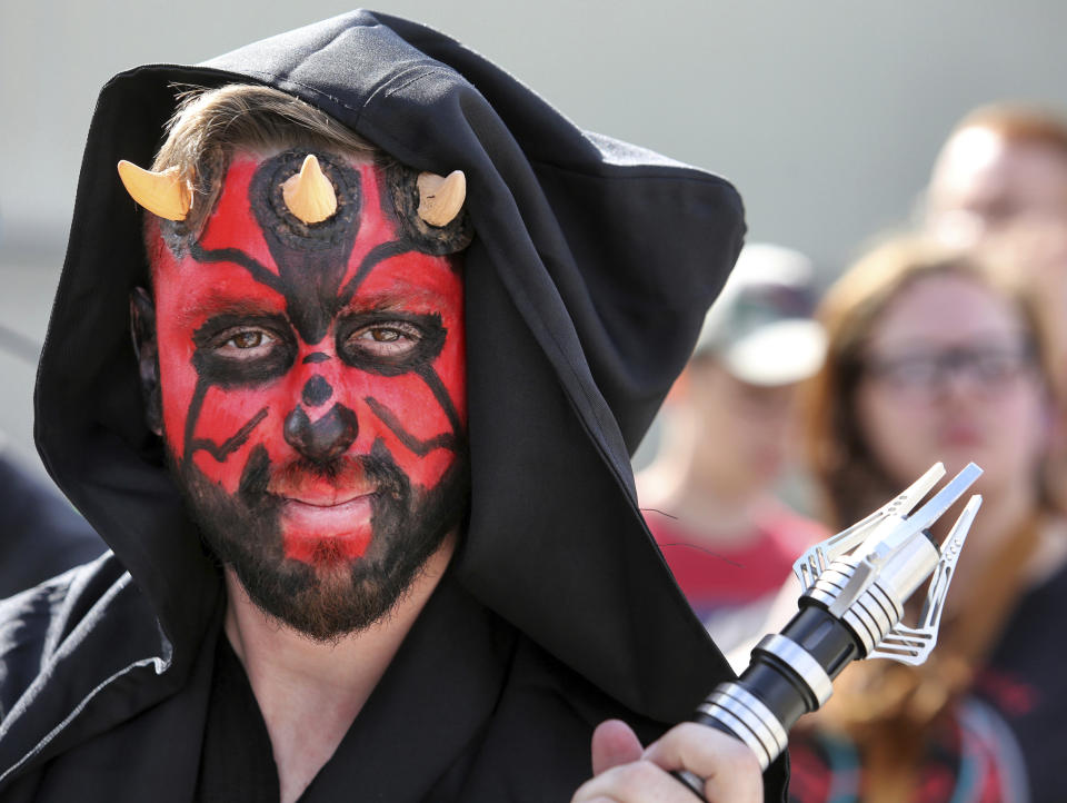 Costumed fans of the Star Wars franchise wait in a massive line outside the Orange County Center, in Orlando, Fla., to attend the 2017 Star Wars Celebration, Thursday, April 13, 2017, marking the 40th anniversary of the original 1977 Star Wars film. Thousands of fans waited for hours in the line, estimated to be more than a mile long. (Joe Burbank/Orlando Sentinel via AP)