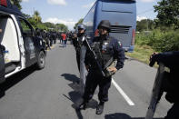 La policía federal mexicana monta guardia en una carretera utilizada por los migrantes centroamericanos con destino a Estados Unidos, que caminan de Ciudad Hidalgo hacia Tapachula, México, el domingo 21 de octubre de 2018. (AP Foto/Moisés Castillo)