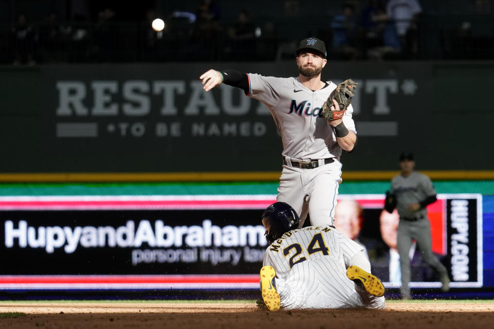 Miami Marlins' Jon Berti, top, turns a double play as Milwaukee Brewers' Andrew McCutchen (24) is tagged out at second base during the ninth inning of a baseball game Sunday, Oct. 2, 2022, in Milwaukee. (AP Photo/Aaron Gash)