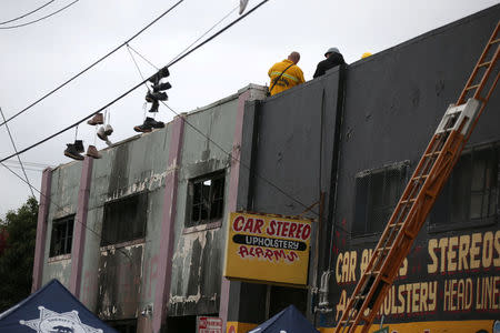 Firefighters work inside the burned warehouse following the fatal fire in the Fruitvale district of Oakland, California, U.S. December 5, 2016. REUTERS/Lucy Nicholson