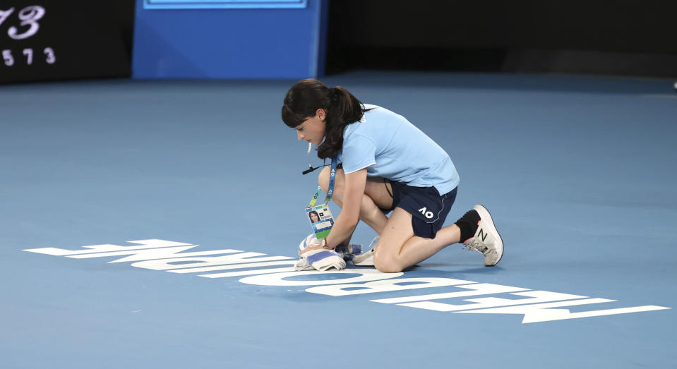 Court staff wipes water from Rod Laver Arena that was dripping from the roof during first round singles matches at the Australian Open tennis championship in Melbourne, Australia, Monday, Jan. 20, 2020. (AP Photo/Lee Jin-man)