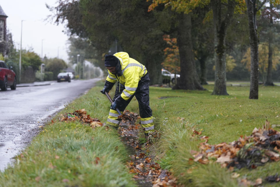 A workman clears a drainage ditch in the village of Edzell, Scotland, ahead of Storm Babet, Thursday Oct. 19, 2023. The UK is bracing for heavy wind and rain from Storm Babet, the second named storm of the season. A rare red weather warning stating there is a "risk to life" has been issued for parts of Scotland as the storm is expected to batter the UK on Thursday. (Andrew Milligan/PA via AP)