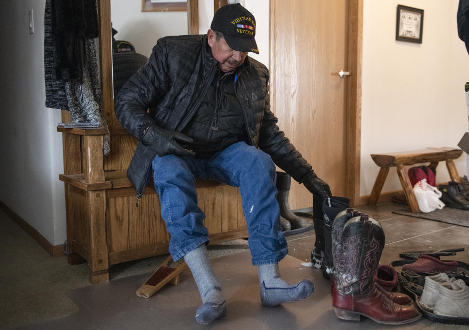 Richard King, 70, takes his boots off after shoveling his deck at his home on the King family ranch near Zortman, Mont., on Sunday, Dec. 8, 2019. King was sexually abused on the Assiniboine reservation in Fort Belknap, Montana, where he grew up. He said taboos and shame kept him silent decades. Instead he abused alcohol and drugs. That, he believes, is how tribal members dealt with the abuses they face, rather than speaking out. (AP Photo/Tommy Martino)