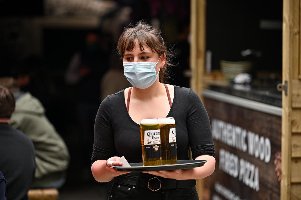 EDINBURGH, SCOTLAND - APRIL 26: A waitress serves members of the public drinks at the Three Sisters Pub in the Cowgate as lockdown measures are eased on April 26, 2021 in Edinburgh, United Kingdom. Cafes, beer gardens, non-essential shops and museums are reopening in Scotland today as lockdown easing continues. (Photo by Jeff J Mitchell/Getty Images)