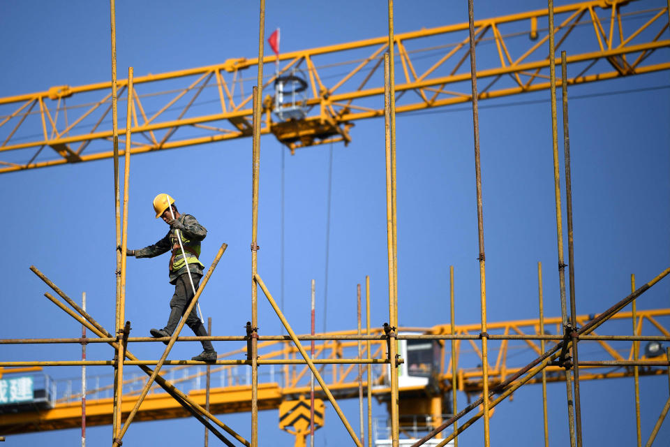 Image: A worker walks along scaffolding at a construction site in Beijing (Noel Celis / AFP - Getty Images)