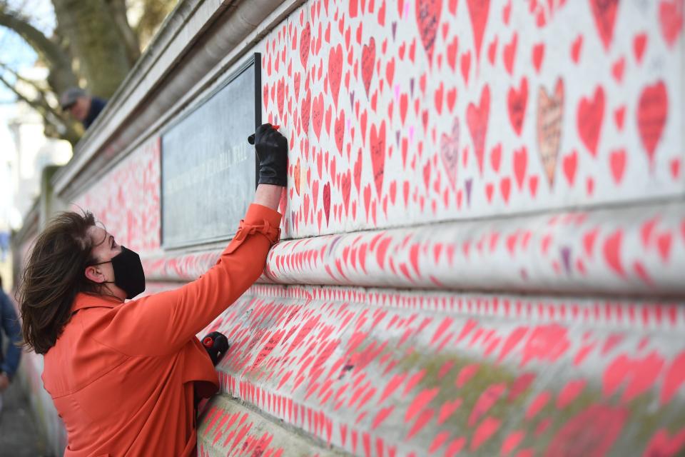 <p>A woman takes part in the final stages of painting approximately 150,000 hearts onto the National Covid Memorial Wall</p> (PA)