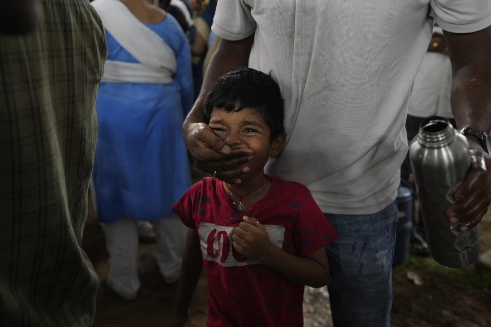 An asthmatic child cries after a live fish stuffed with a herbal paste was inserted into his mouth, in Hyderabad, India, Saturday, June 8, 2024. Every year thousands of asthma patients arrive here to receive this fish therapy from the Bathini Goud family, a secret formula of herbs, handed down by generations only to family members. The herbs are inserted in the mouth of a live sardine, or murrel fish, and slipped into the patient's throat. (AP Photo/Mahesh Kumar A.)