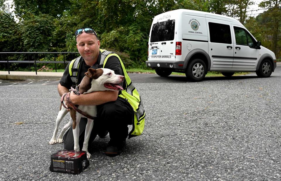 Milford Animal Control Officer Keith Haynes comforts "Abby," a 3-year-old pit bull that is up for adoption, Sept. 21, 2022. Milford Animal Control has recently taken in more dogs than usual, which has created a shortage of dog food.