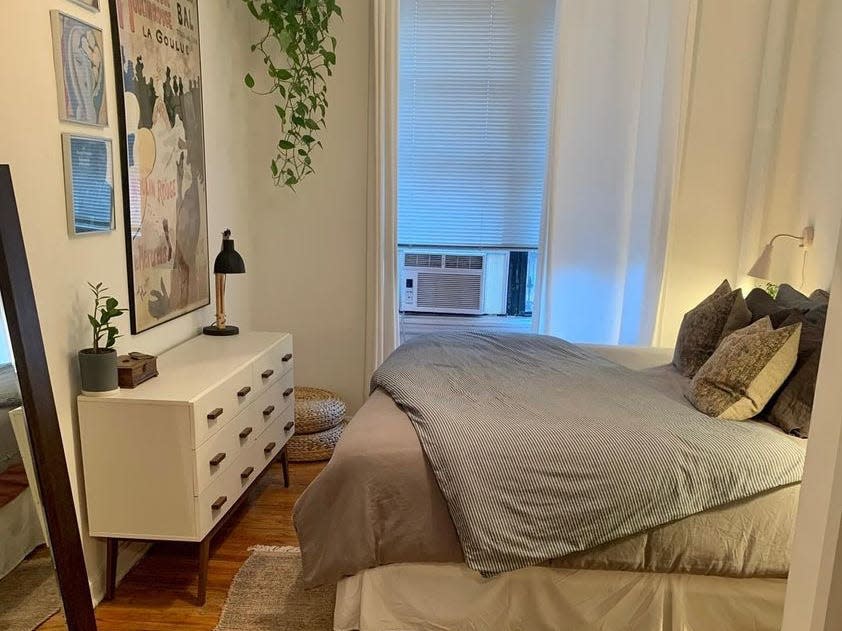 Neutral bedroom with gray sheets on bed and faux plant hanging in corner of room