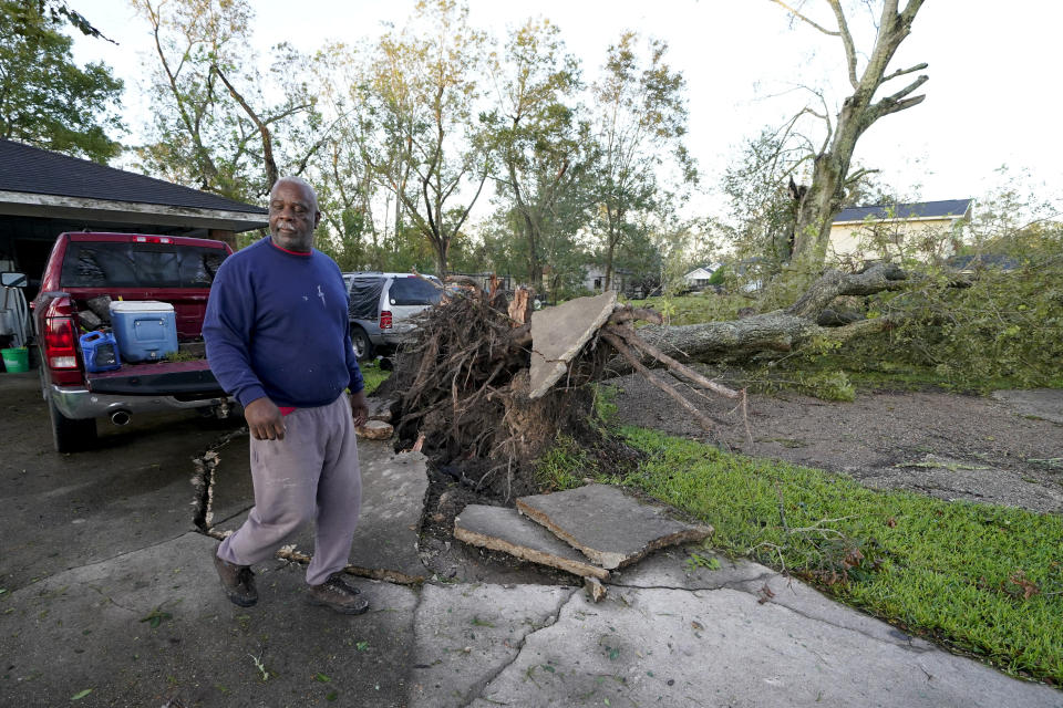 Marcus Peterson walks past a downed tree in his yard after Hurricane Delta moved through, Saturday, Oct. 10, 2020, in Jennings, La. Delta hit as a Category 2 hurricane with top winds of 100 mph (155 kph) before rapidly weakening over land. (AP Photo/Gerald Herbert)