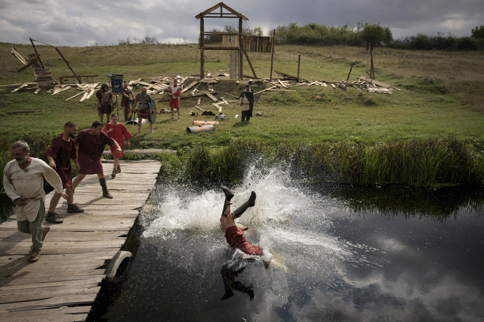 A man wearing a Roman soldier outfit is thrown into a river during a battle at the Romula Fest historic reenactment festival in the village of Resca, Romania, Sunday, Sept. 4, 2022. (AP Photo/Andreea Alexandru)