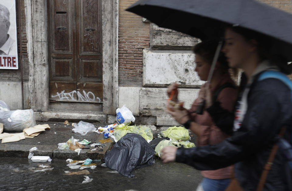 People walk past garbage abbandoned on a sidwalk, in Rome, Monday, Nov. 5, 2018. Rome’s monumental problems of garbage and decay exist side-by-side with Eternal City’s glories. (AP Photo/Gregorio Borgia)