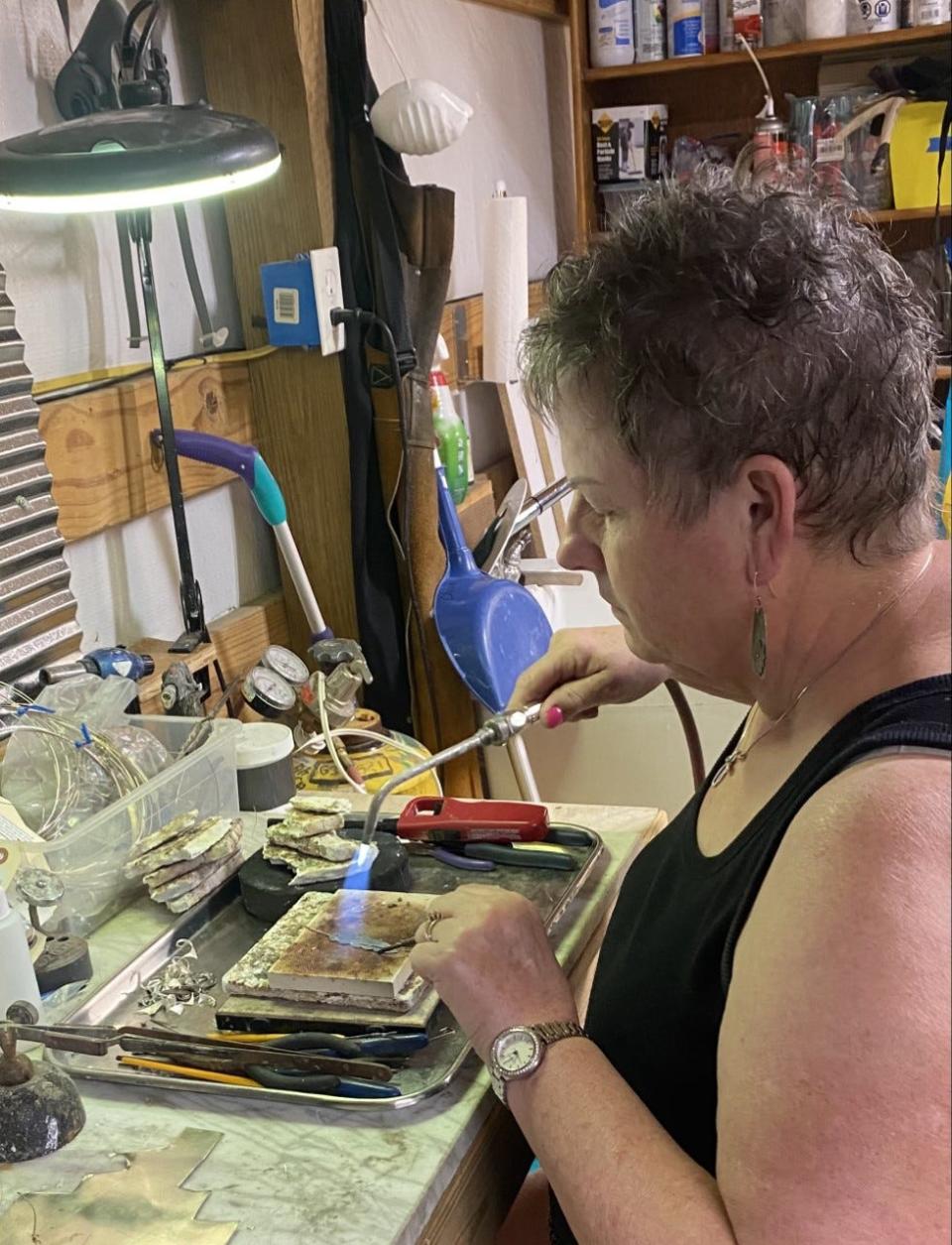 Mary Lou Christie, a silversmith from Tahlequah, Oklahoma, works on her latest jewelry piece in her home workshop.