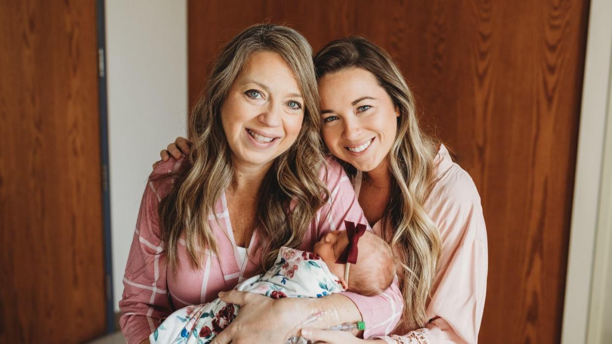 a couple of women holding a baby