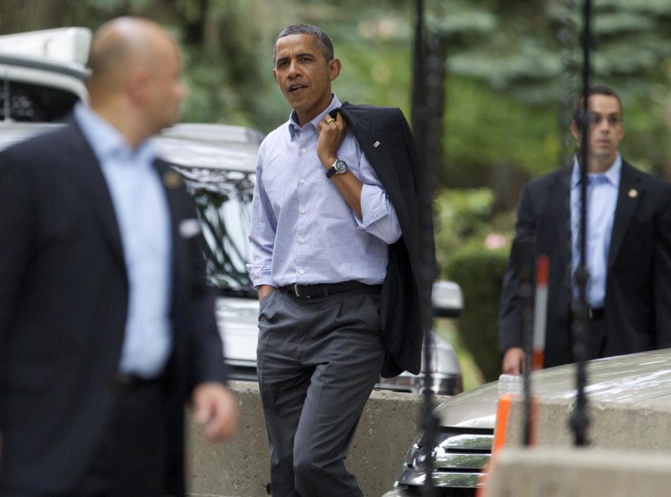 President Barack Obama, center, walks through his Hyde Park neighborhood to a campaign event, Sunday, Aug. 12, 2012, in Chicago. (AP Photo/Carolyn Kaster)