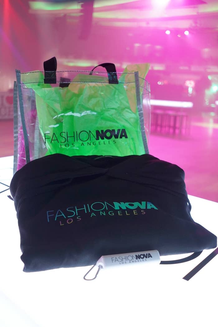 A Fashion Nova Los Angeles tote bag and drawstring bag are displayed on a table in a brightly lit room