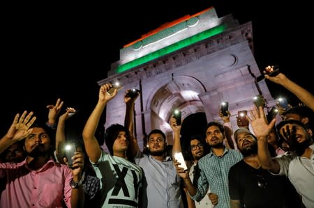 People hold their mobile phone torches as they take part in a protest demanding investigation in a highway collision in which a woman who is fighting a rape case against a legislator of the ruling BJP party was critically injured, in New Delhi