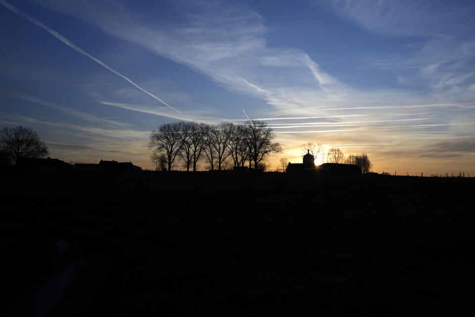 The sun begins to rise over a farmhouse near Ledegem, Belgium, Tuesday, Feb. 13, 2024. Fickle regulations are a key complaint heard from European farmers protesting over the past weeks, setting up a key theme for the upcoming June 6-9 parliamentary elections in the 27-nation European Union. (AP Photo/Virginia Mayo)