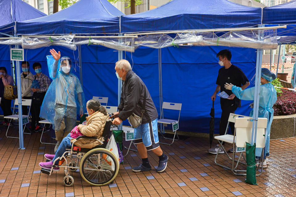 HONG KONG, CHINA - 2022/03/25: A man pushes a woman in a wheelchair who is about to receive her second dose of Pfizer-BioNTech COVID-19 vaccine at a mobile vaccination station in Tin Shui Wai in Hong Kong. (Photo by Emmanuel Serna/SOPA Images/LightRocket via Getty Images)