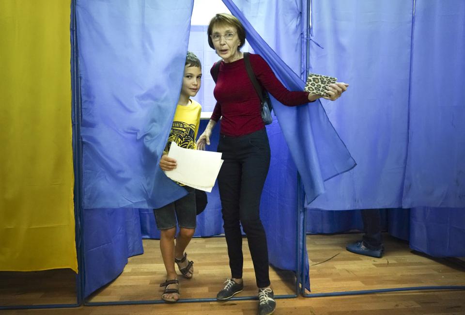 A woman and a boy leave a booth at a polling station during at a parliamentary election in Kiev, Ukraine, Sunday, July 21, 2019. The party of new President Volodymyr Zelenskiy is widely predicted to get the largest share of votes in Sunday's election. (AP Photo/Evgeniy Maloletka)