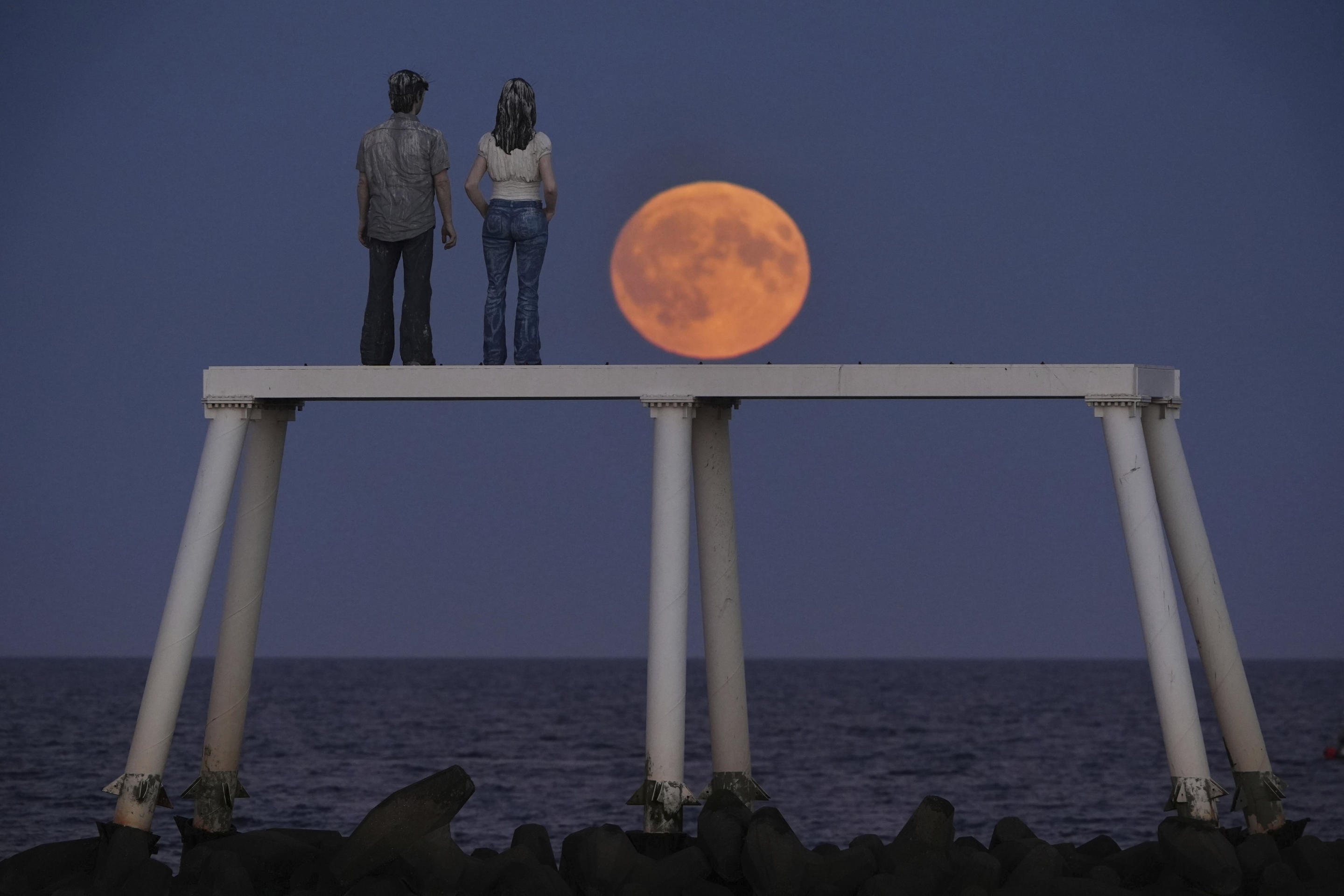 The full Harvest moon rises over 'The Couple' sculpture at Newbiggin-by-the-Sea in Northumberland, England on Sept. 17. (Owen Humphreys/PA via AP)