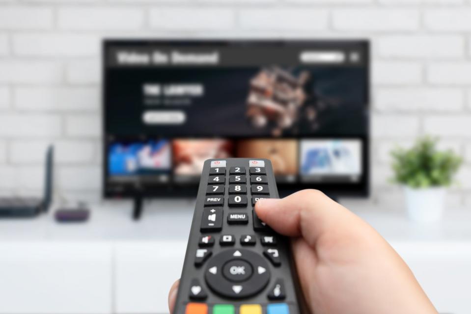 A person holding a remote at a Smart TV.