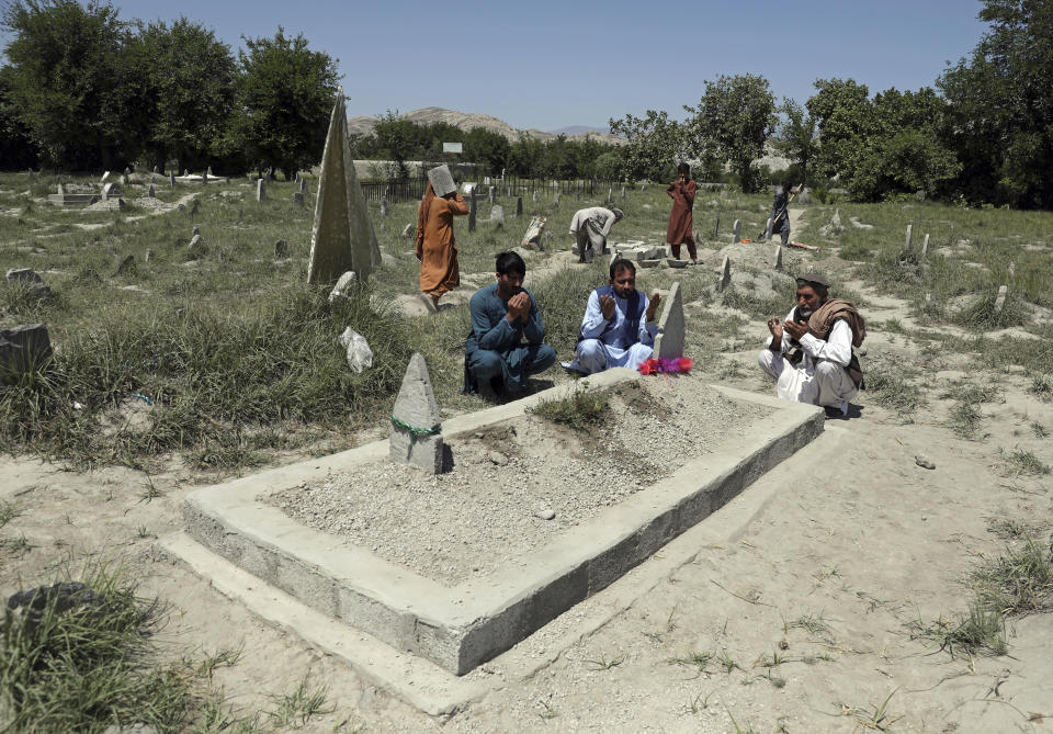 Abdul Rauf right, prays over the grave of his daughter Shahnaz Raufi, a worker at a TV station who was killed in a March attack claimed by the Islamic State group, in Jalalabad, Afghanistan, Wednesday, April 21, 2021. IS has resumed a campaign of targeted killings of minority Shiite Muslims, many of them ethnic Hazaras, as well as women's rights activists and media workers. (AP Photo/Rahmat Gul)