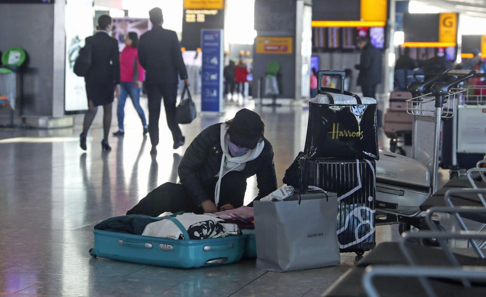 A woman wearing a face mask packs her suitcase in the departures area of Terminal 5 at Heathrow Airport, after it was announced British Airways has suspended all services to and from China. (Photo by Steve Parsons/PA Images via Getty Images)