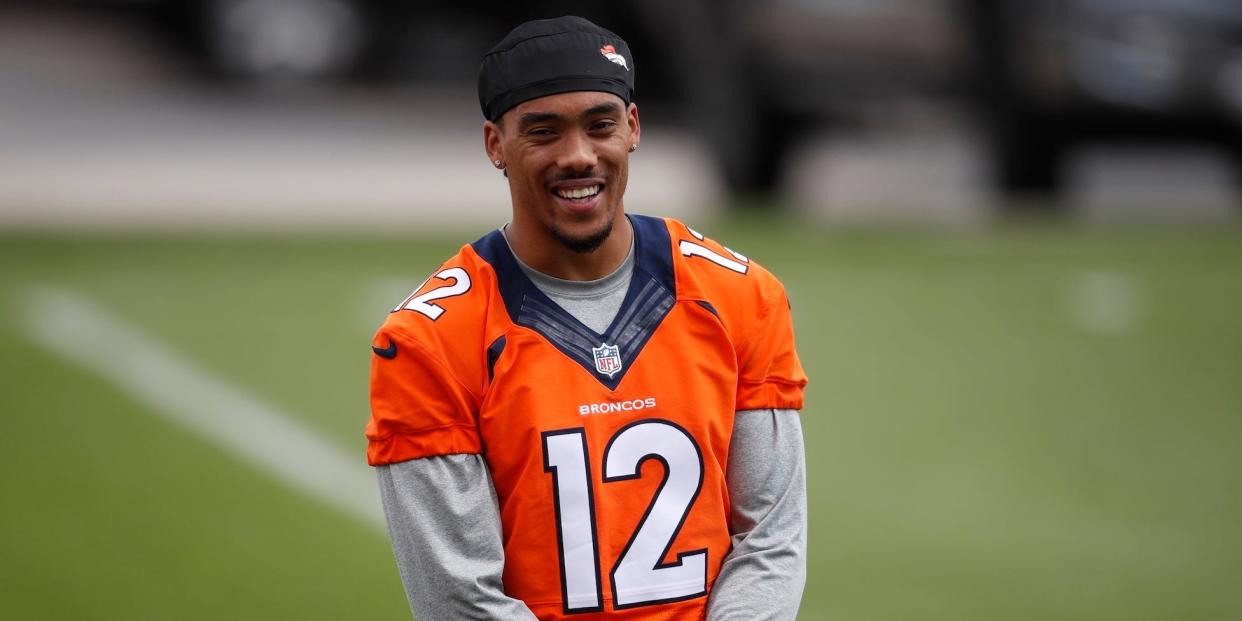 Brendan Langley smiles on a pitch while wearing a Denver Broncos shirt