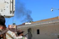 Fighters from Libyan forces allied with the U.N.-backed government take position as smoke rises during a battle with Islamic State militants in Sirte, Libya. REUTERS/Ismail Zitouny