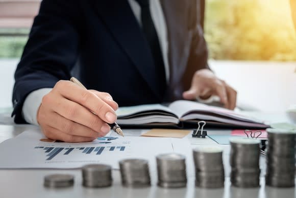 BUsinessman writing on a graph with money in front of him