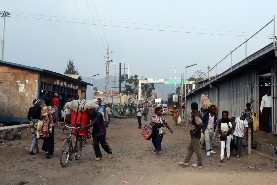 People walk past the Congo side of the Poids Lourd checkpoint at the border between Congo and Rwanda, Thursday, Aug. 1, 2019. Congo's presidency says the border is open again with Rwanda hours after its eastern neighbor closed it over the deadly Ebola outbreak. The closure occurred Thursday morning as the first case of direct transmission of the Ebola virus was confirmed in Goma, the Congo city of more than 2 million people on the Rwandan border.(AP Photo)