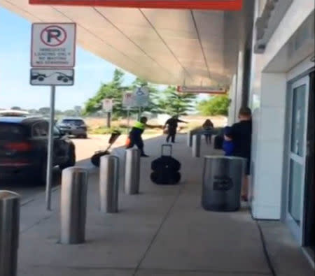 A still image from video released on June 10, 2016 shows a police officer aiming his weapon (background) after opening fire on a man, who authorities say was involved in a domestic dispute, at Love Field, in Dallas, Texas, U.S. MANDATORY CREDIT Bryan Armstrong@flashyfilms/Handout via REUTERS