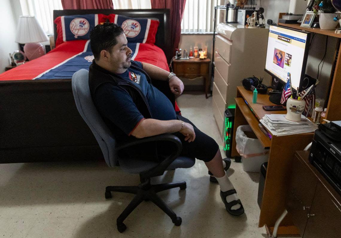 Rudens Rodríguez sits in front of the desk that holds his computer. He broke one of the desk’s legs when he leaned on it to avoid falling. Now the desk is supported by a box of cigars and needs to be replaced.