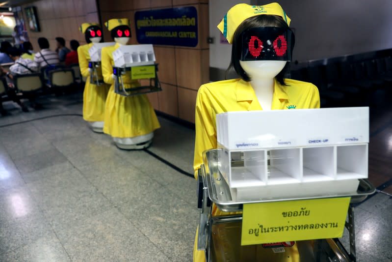 FILE PHOTO: Robots wearing nurse costumes carry medical documents at Mongkutwattana General Hospital in Bangkok