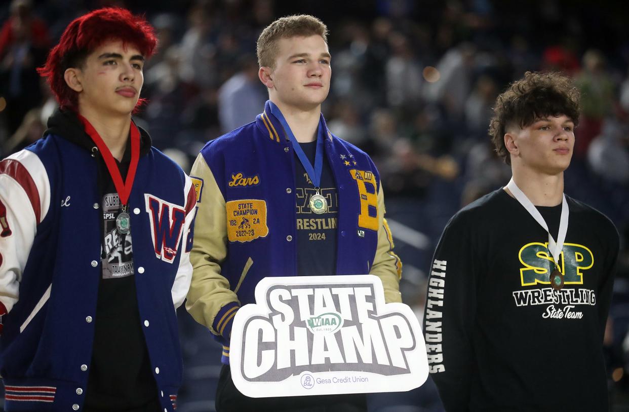 Bremerton’s Lars Michaelson, center, takes first place on the podium as the 2A 190-pound champion at Mat Classic on Friday, Feb. 17, 2024.