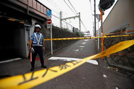 Police officer stands guard near the site after a train derailed during a collision with a truck in Yokohama, near Tokyo