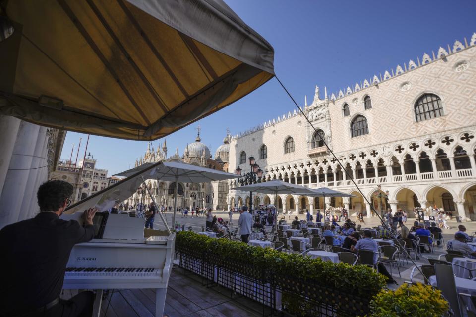 A man plays piano at the historical Cafe Florian, in St. Mark's square, in Venice, Italy, Thursday, June 17, 2021. After a 15-month pause in mass international travel, Venetians are contemplating how to welcome visitors back to the picture-postcard canals and Byzantine backdrops without suffering the indignities of crowds clogging its narrow alleyways, day-trippers perched on stoops to imbibe a panino and hordes of selfie-takers straining for a spot on the Rialto Bridge or in front of St. Mark’s Basilica. (AP Photo/Luca Bruno)